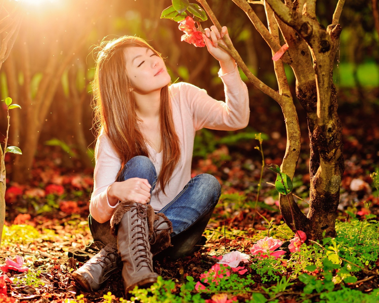 Девушка сидит на земле под ярким солнцем в лесу