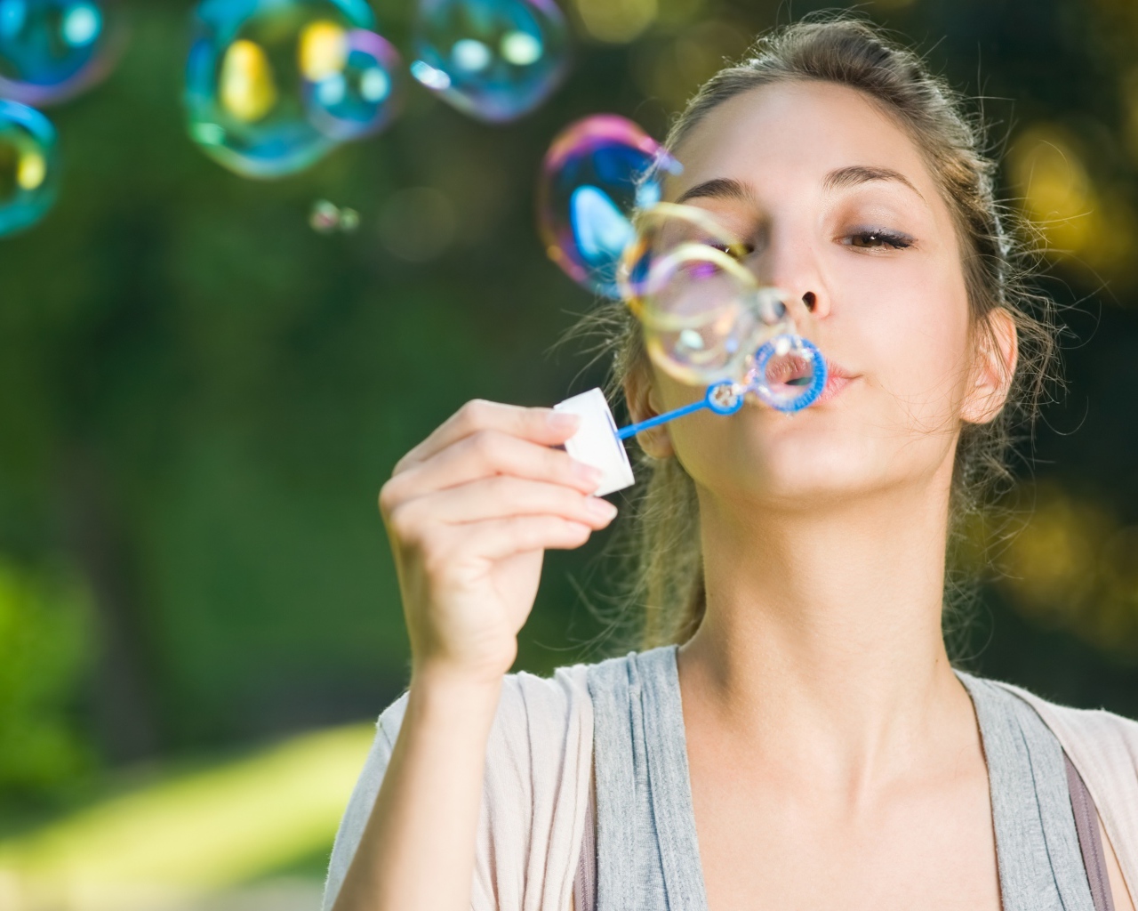 Милая молодая девушка пускает мыльные пузыри