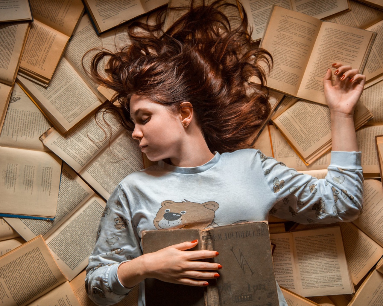 Молодая девушка спит на книгах