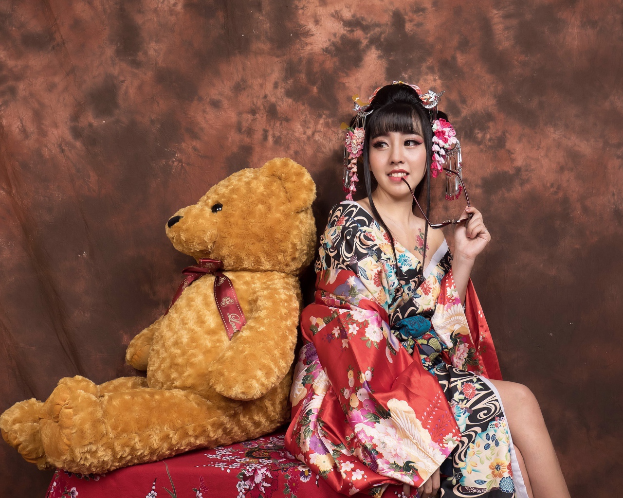 Девушка азиатка сидит с большим плюшевым медведем
