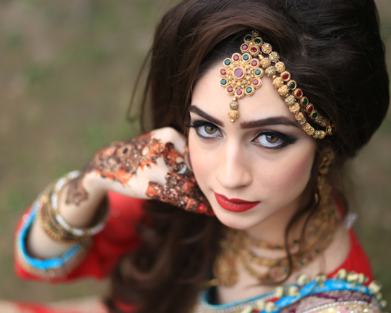 Красивая кареглазая девушка в индийском костюме с рисунками на руках 