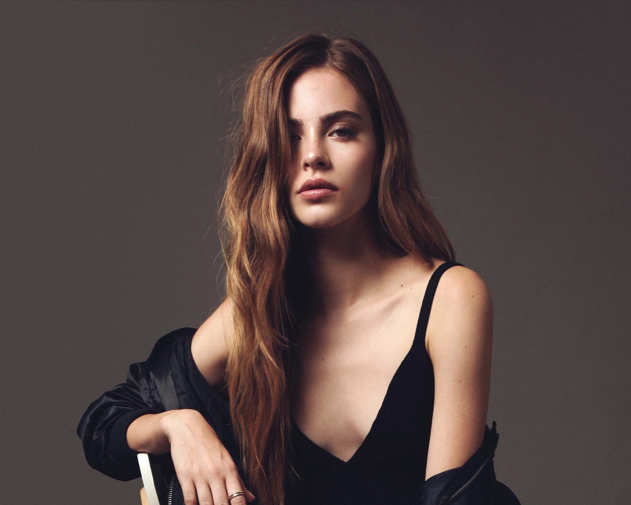 Красивая брюнетка в черном платье сидит на стуле