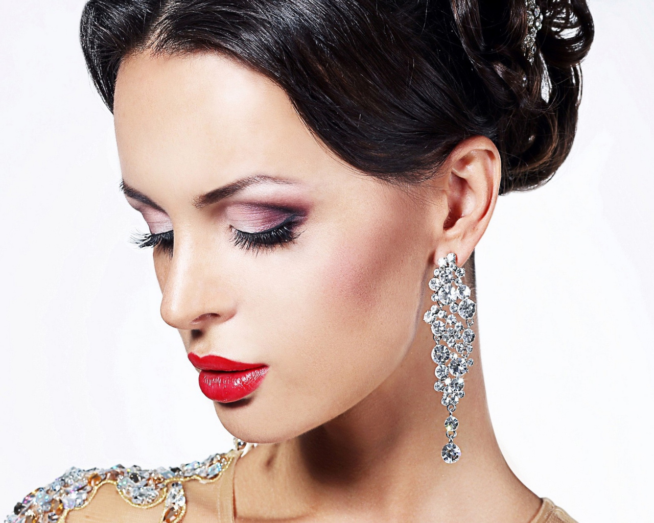 Красивая брюнетка в дорогих украшениях на белом фоне