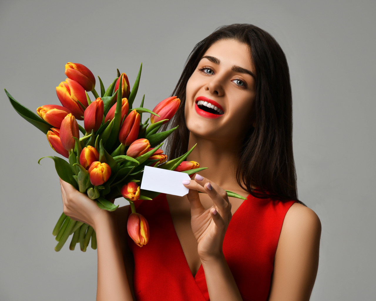 Красивая брюнетка с букетом тюльпанов на сером фоне