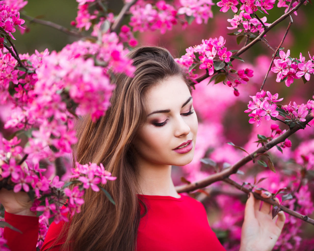 Красивая нежная шатенка у цветущей розовыми цветами ветки