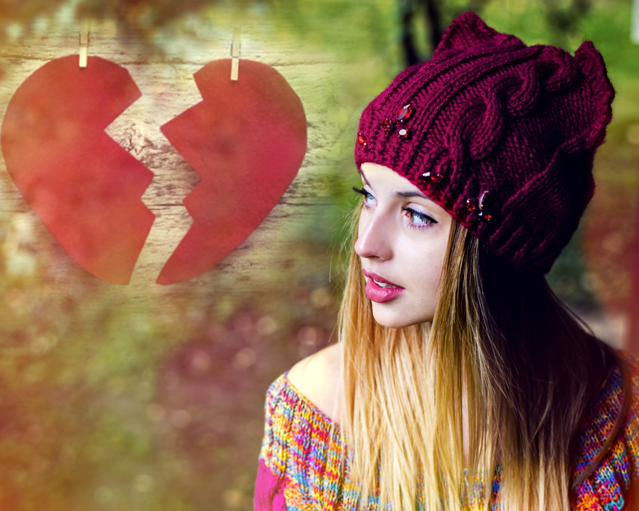 Красивая девушка в вязаной шапке на фоне разбитого сердца