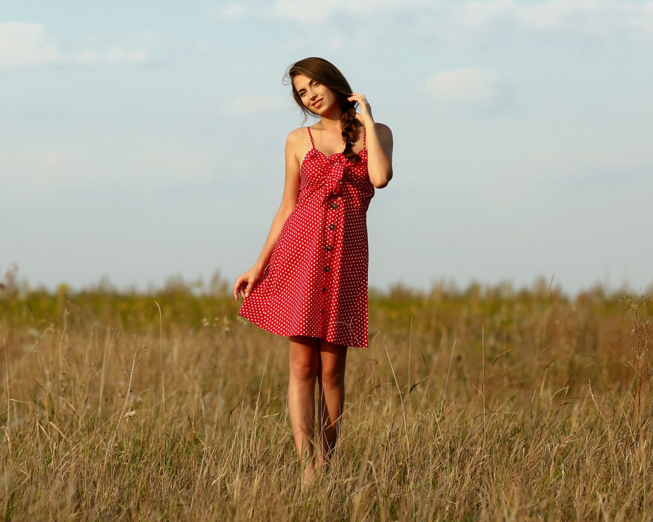 Красивая девушка в красном сарафане на поле 