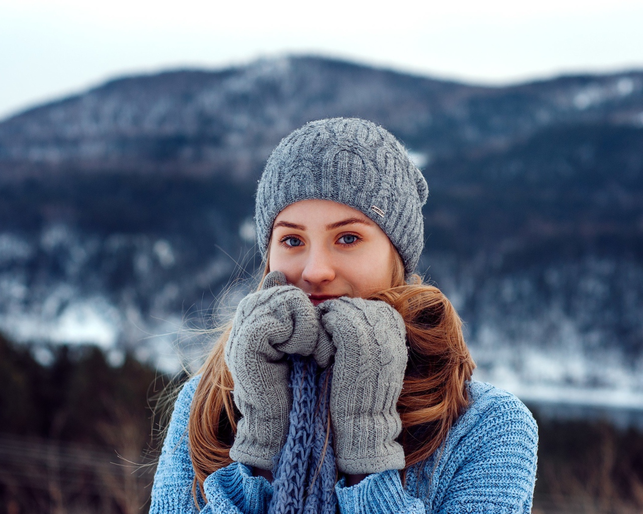 Красивая девушка в теплой шапке и варежках