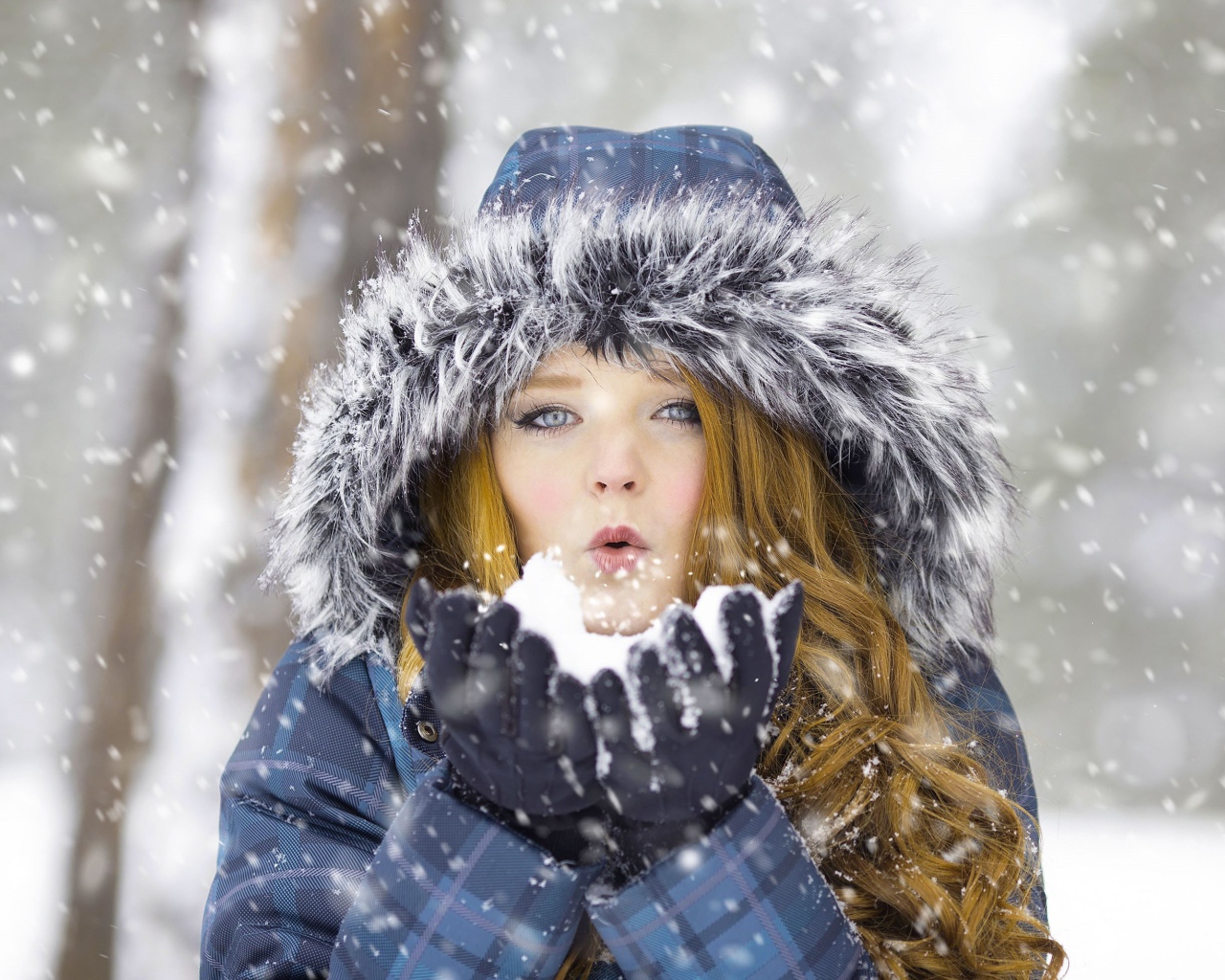 Красивая девушка в теплой куртке со снегом в руках