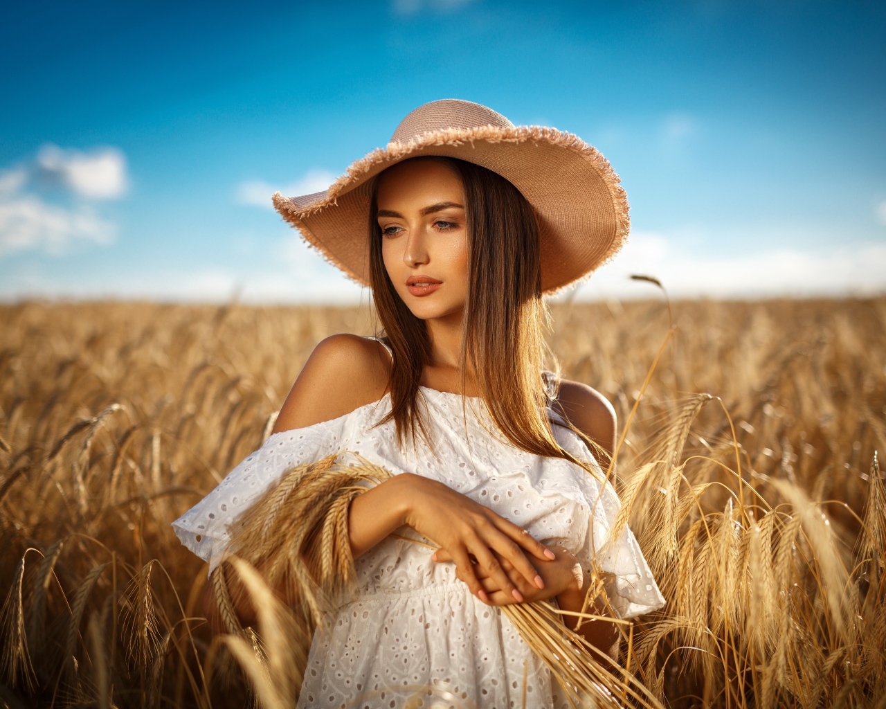 Красивая девушка в белом платье с колосьями пшеницы