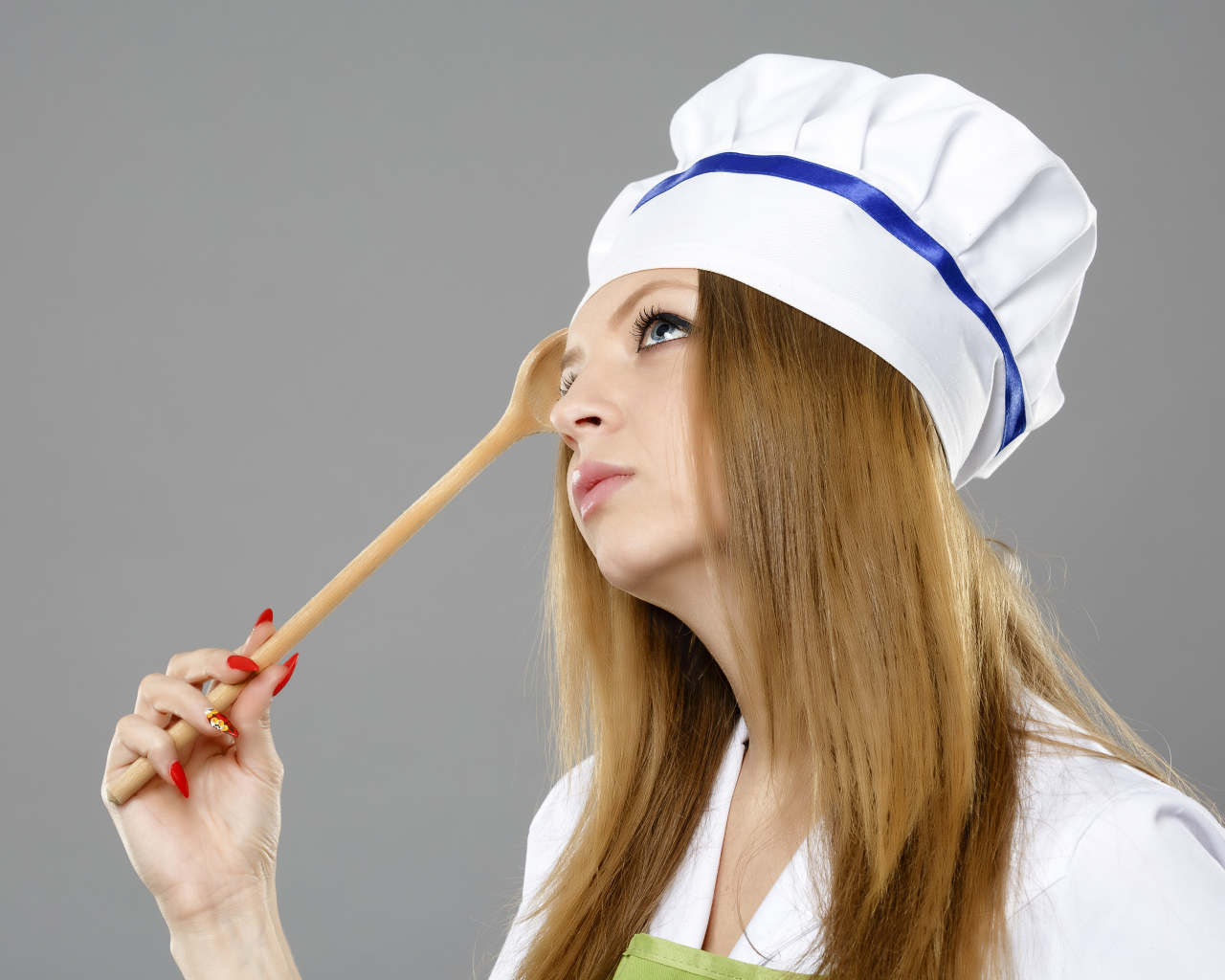 Красивая девушка в костюме повара на сером фоне