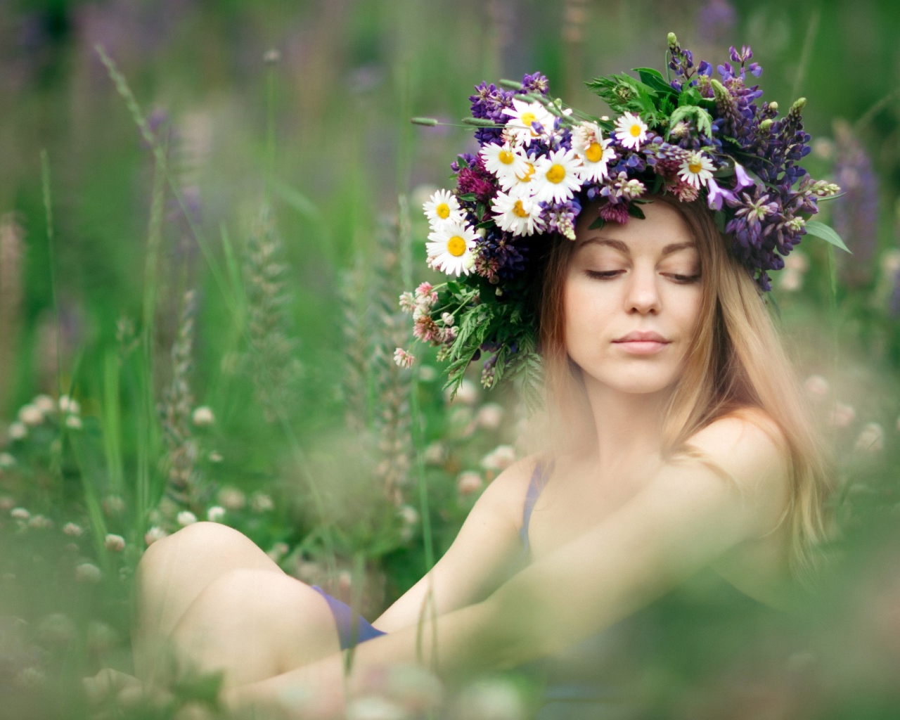 Красивая девушка с венком из полевых цветов на голове летом 