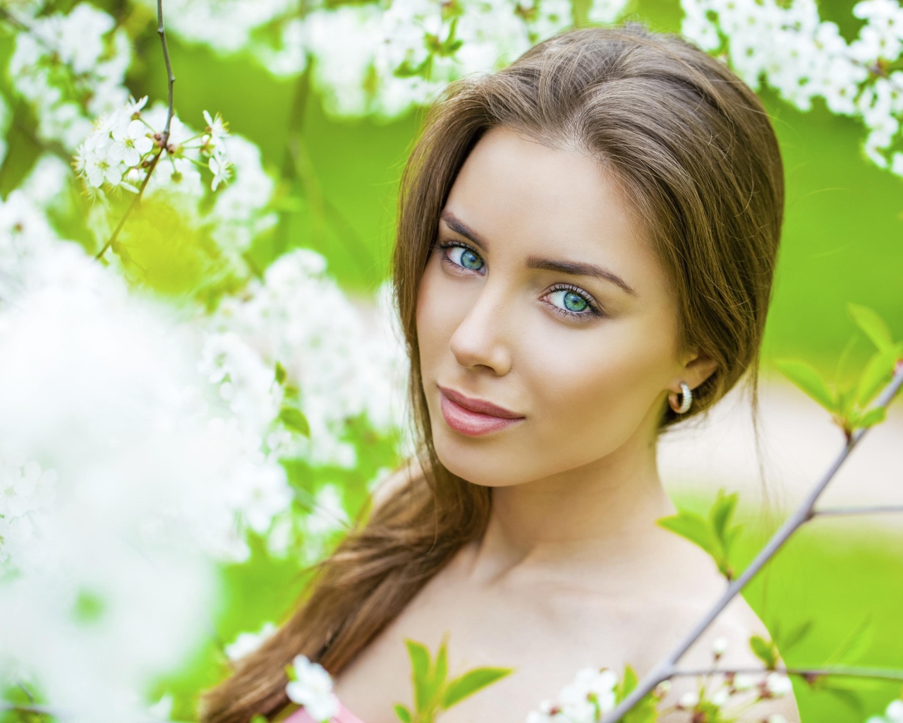 Красивая зеленоглазая девушка у цветущей вишни 