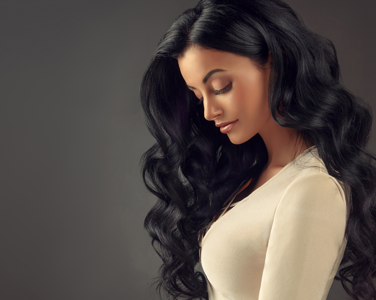 Красивая длинноволосая брюнетка на сером фоне