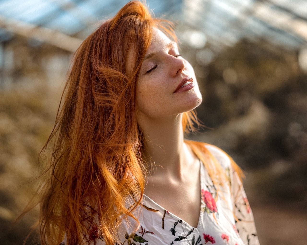 Красивая рыжеволосая девушка нежится в лучах солнца