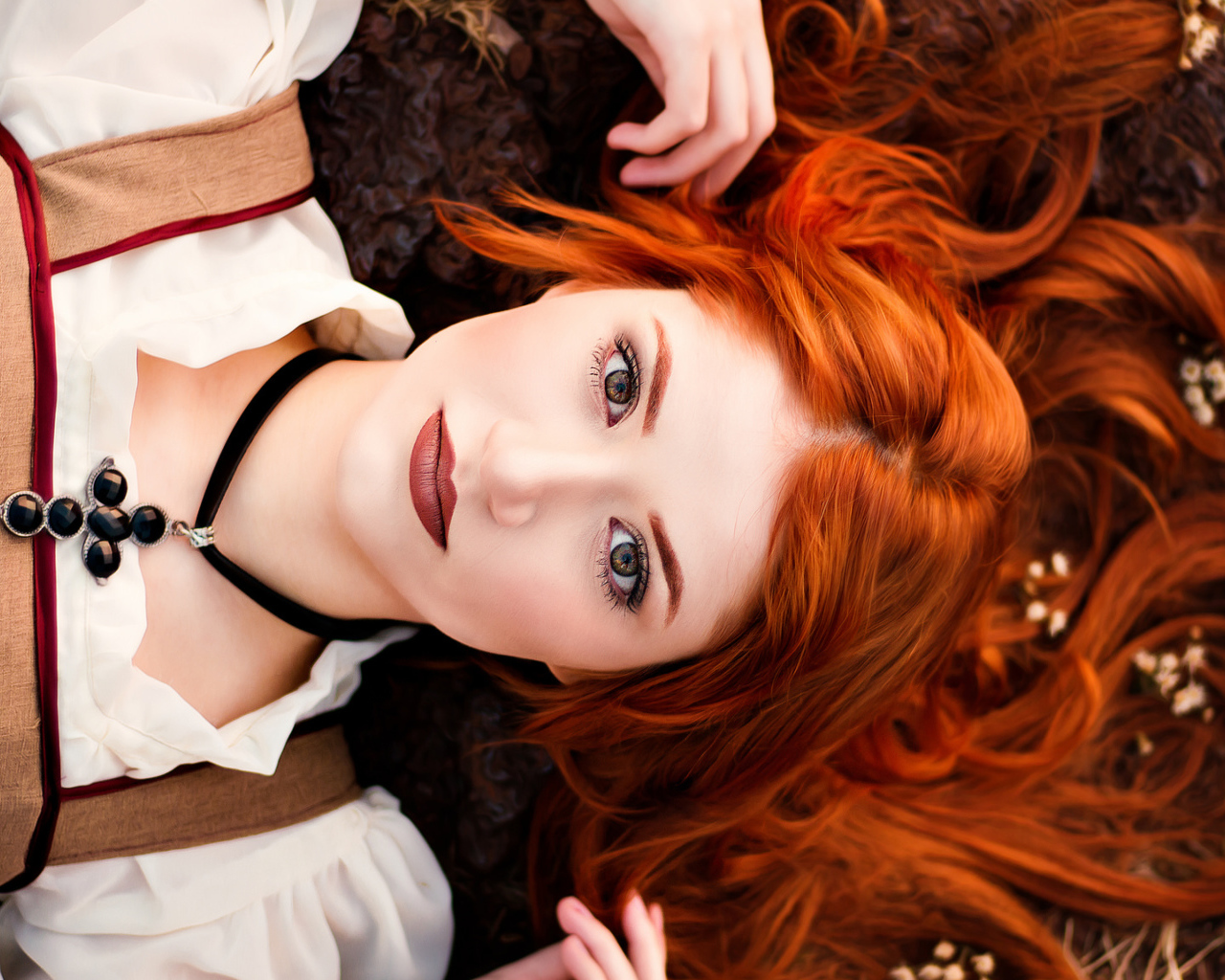 Красивая рыжеволосая девушка лежит на земле 