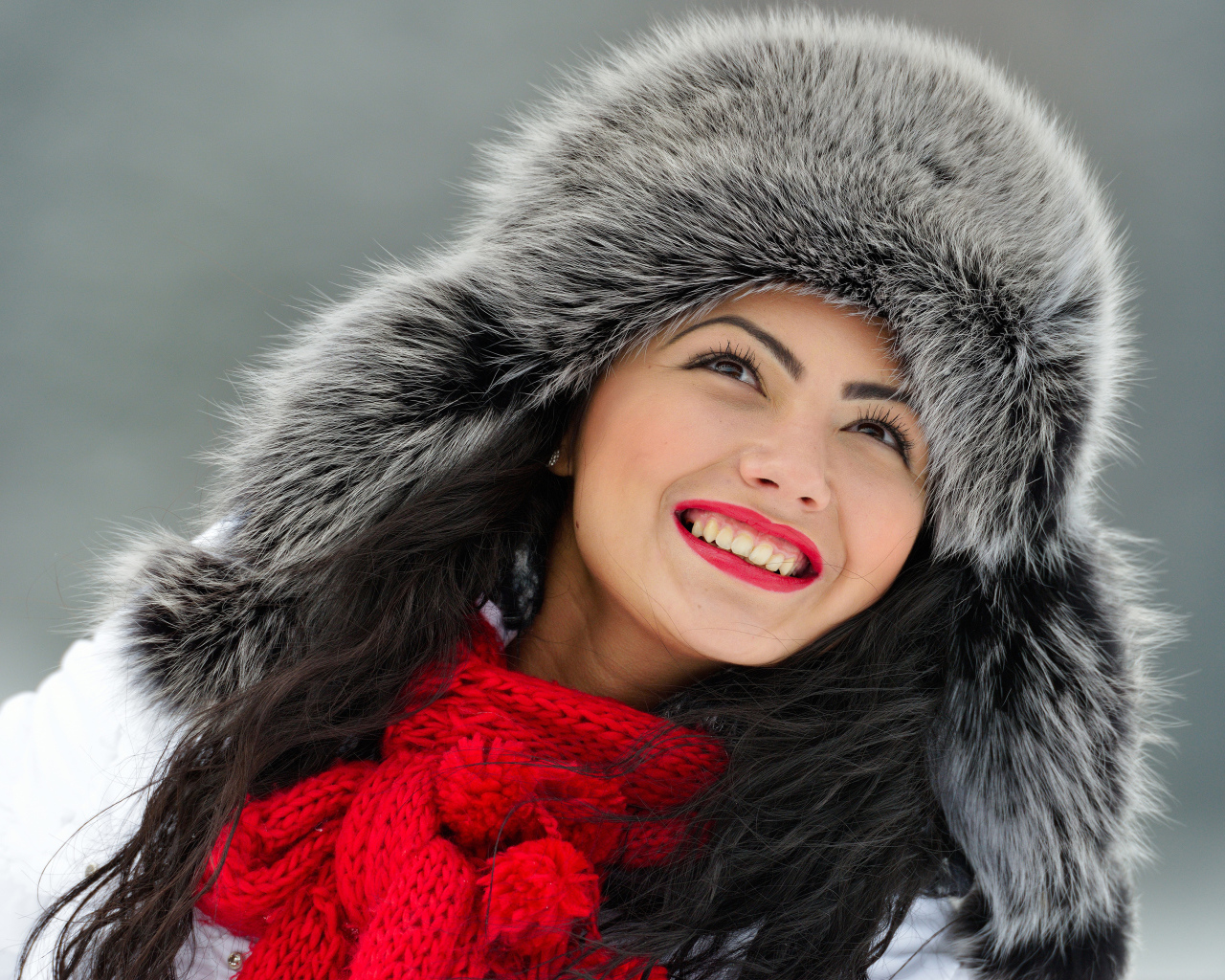 Красивая улыбающаяся брюнетка в теплой зимней шапке