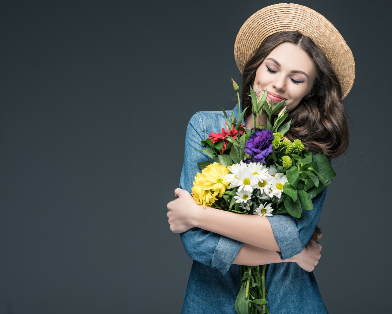 Красивая улыбающаяся девушка в шляпе с букетом цветов