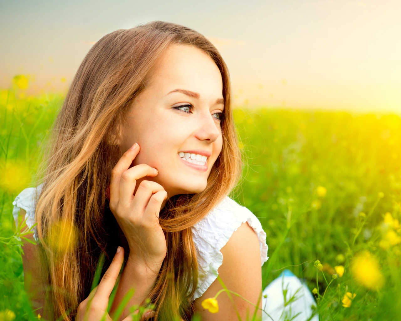 Красивая улыбающаяся молодая девушка лежит в зеленой траве