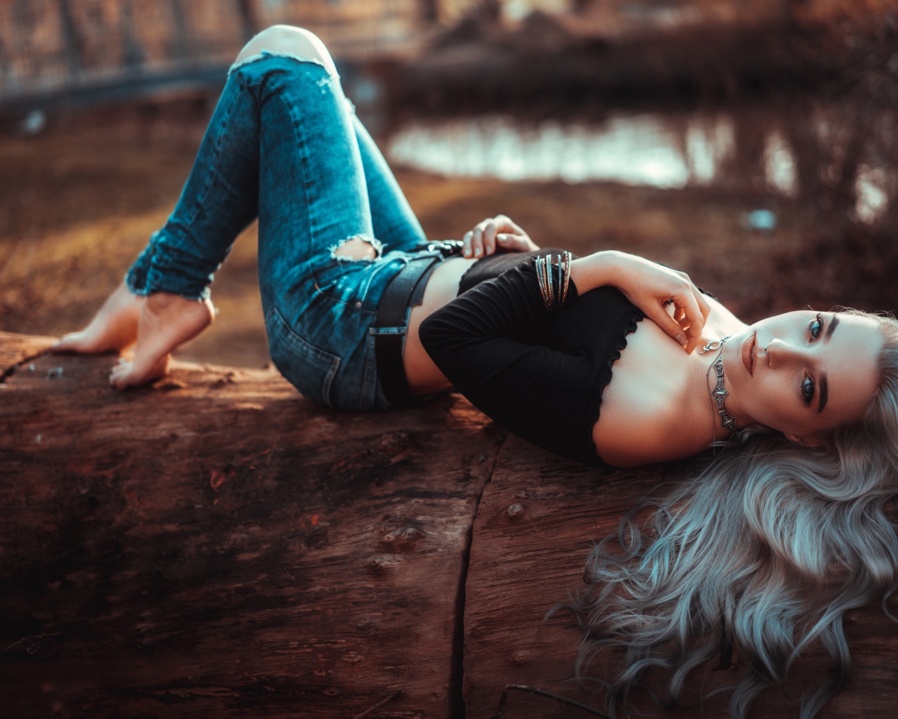 Красивая молодая блондинка лежит на сухом дереве