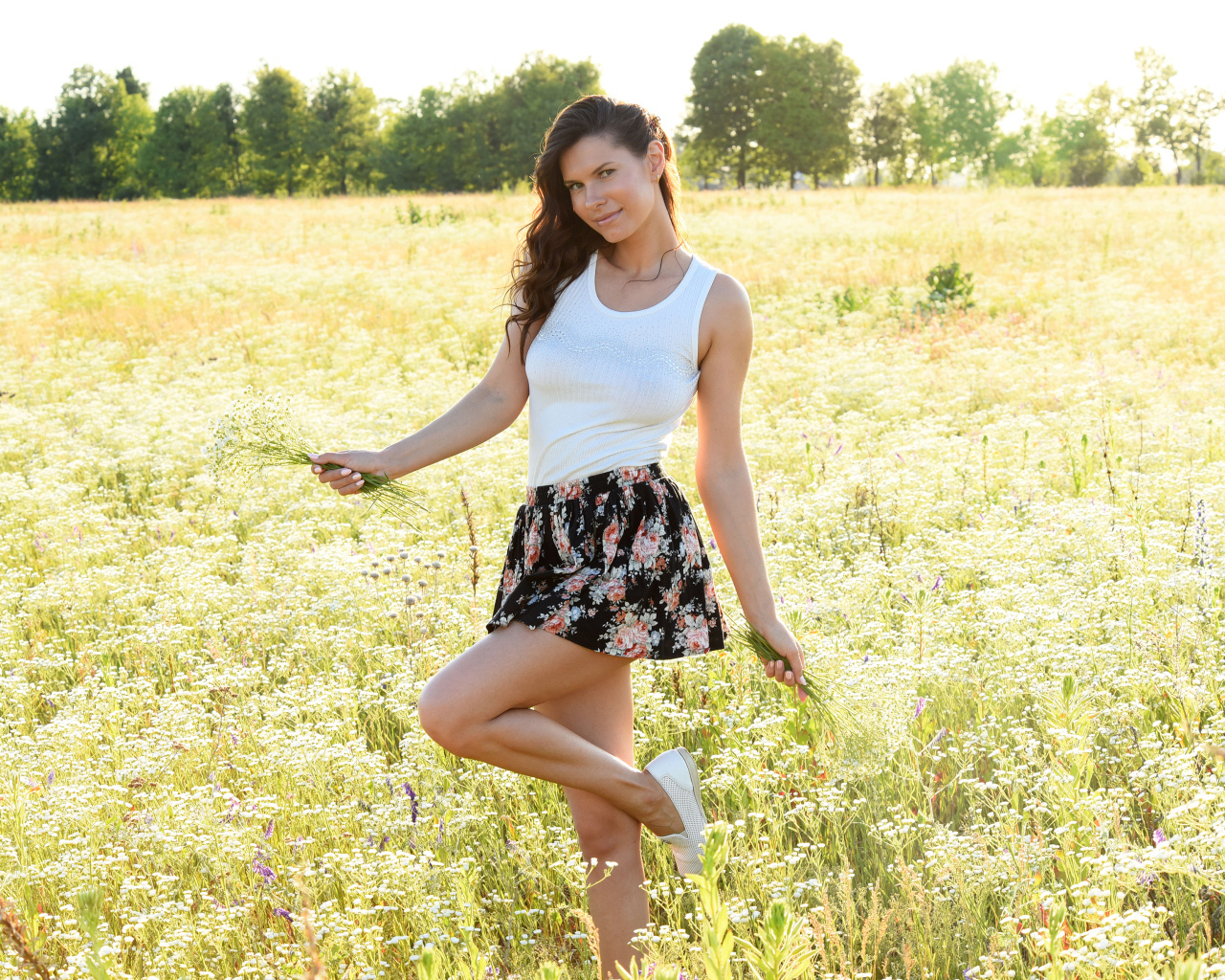 Красивая молодая девушка на поле с белыми ромашками