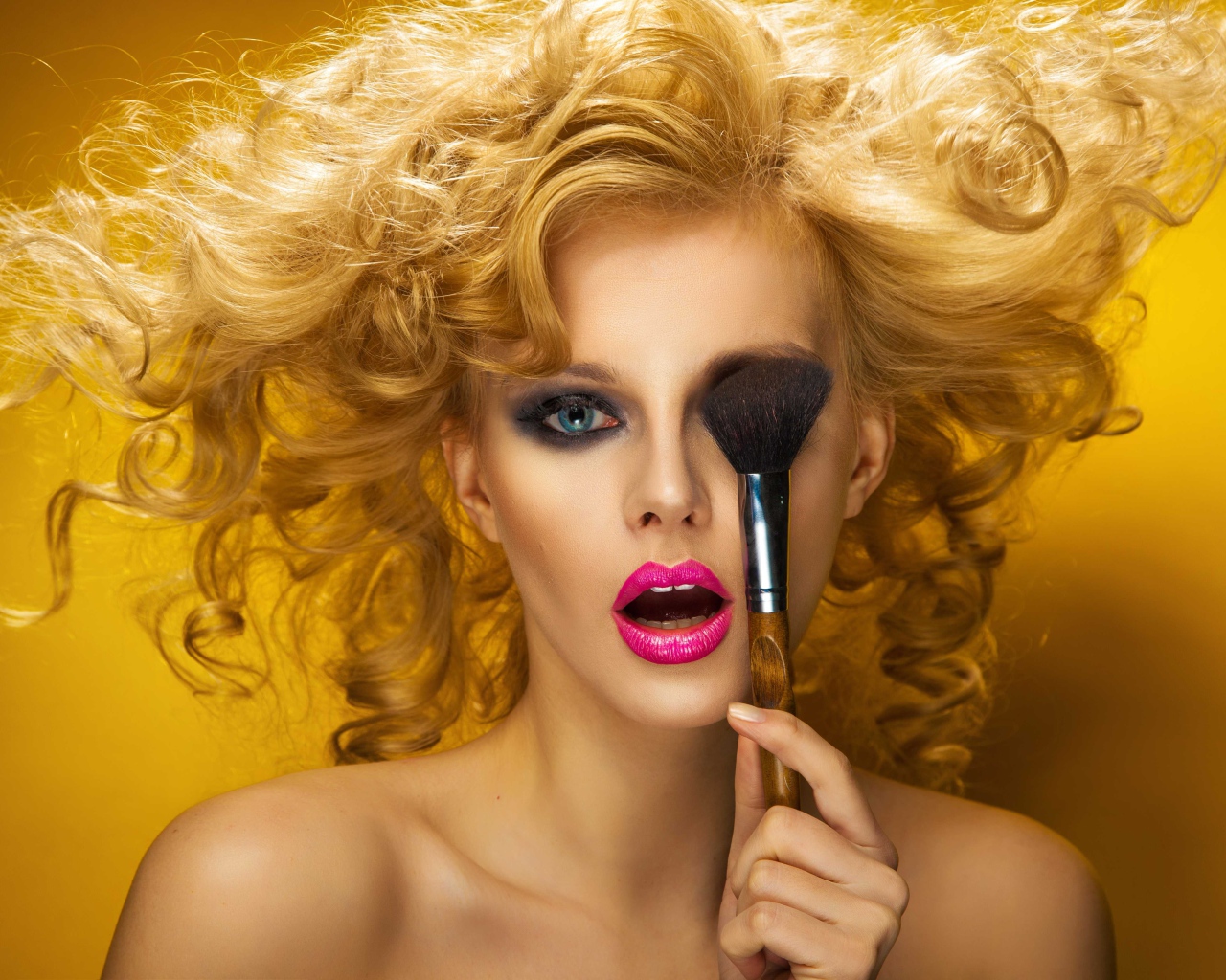 Блондинка с ярким макияжем с кистью у лица