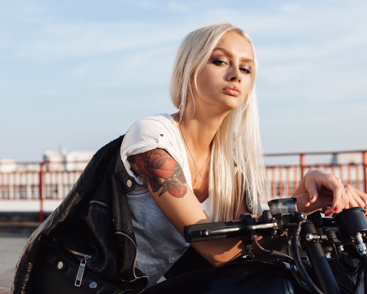 Брутальная блондинка с татуировкой на руке на мотоцикле 
