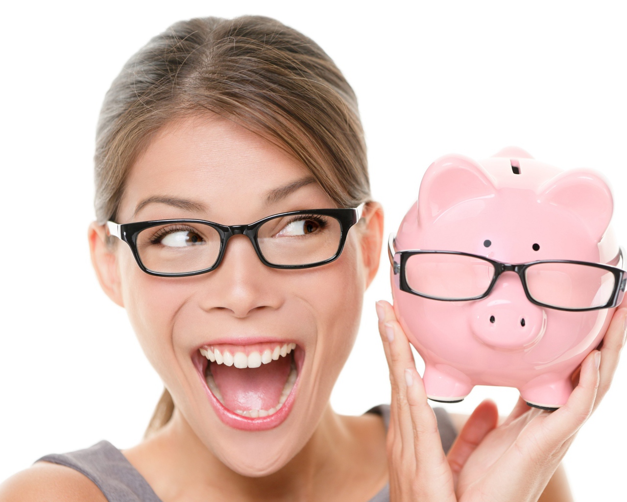 Веселая девушка в очках с копилкой в руках на белом фоне