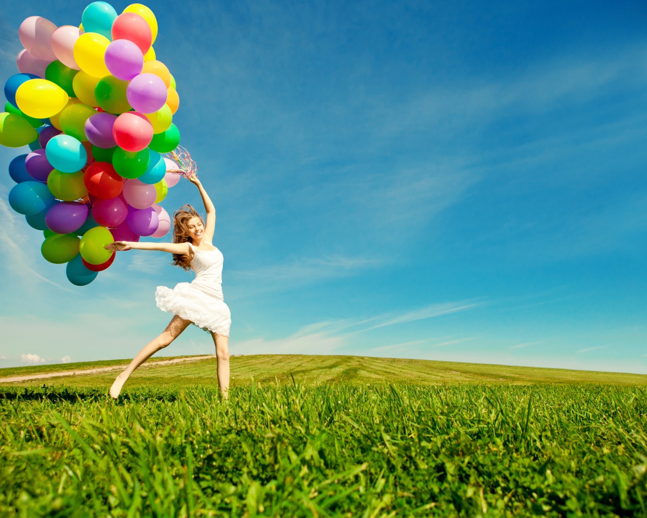Веселая девушка в белом платье с разноцветными воздушными шариками