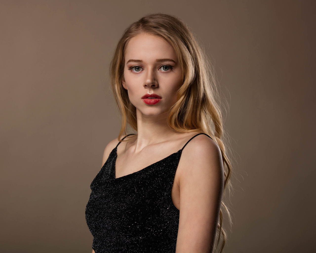 Нежная девушка модель в черном платье на сером фоне