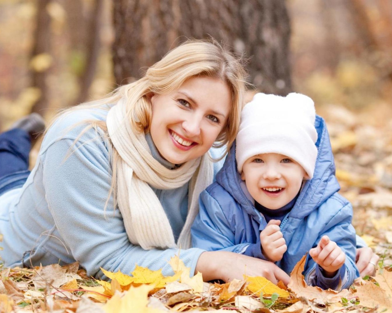 Мать с сыном лежат на листве осенью