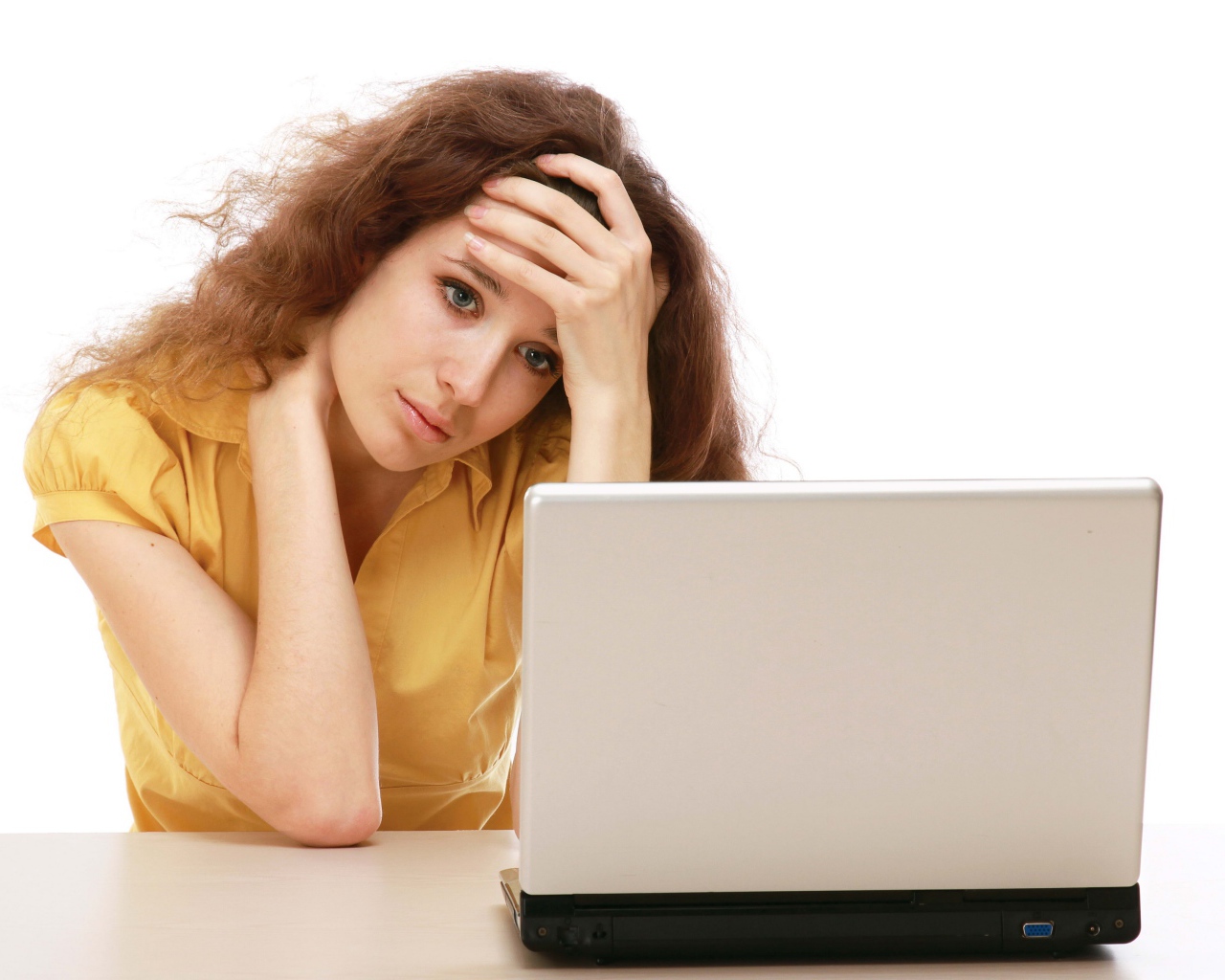 Грустная девушка сидит возле ноутбука 