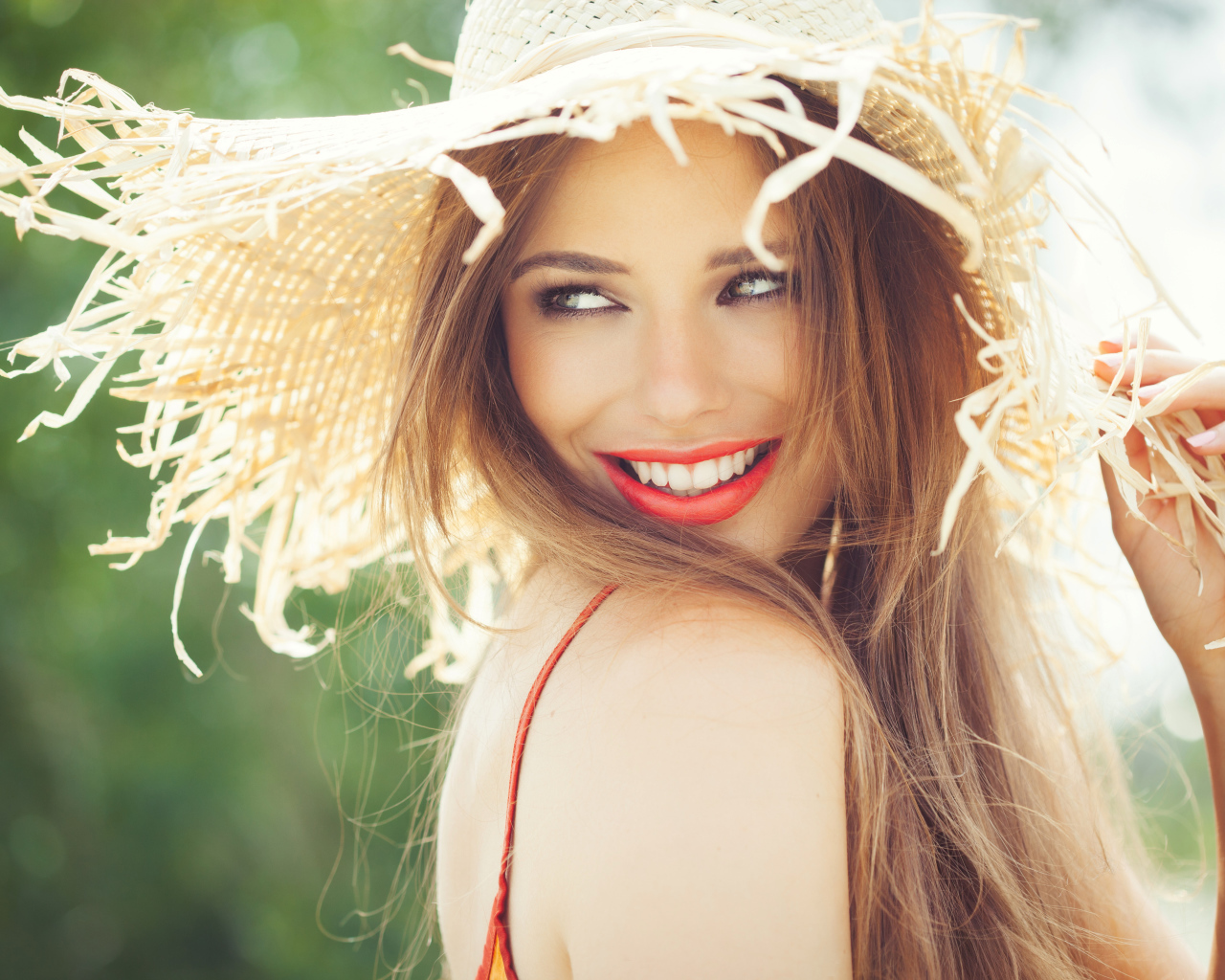 Улыбающаяся девушка в соломенной шляпе летом