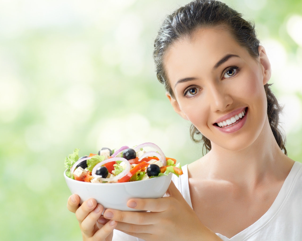 Улыбающаяся девушка с тарелкой овощного салата