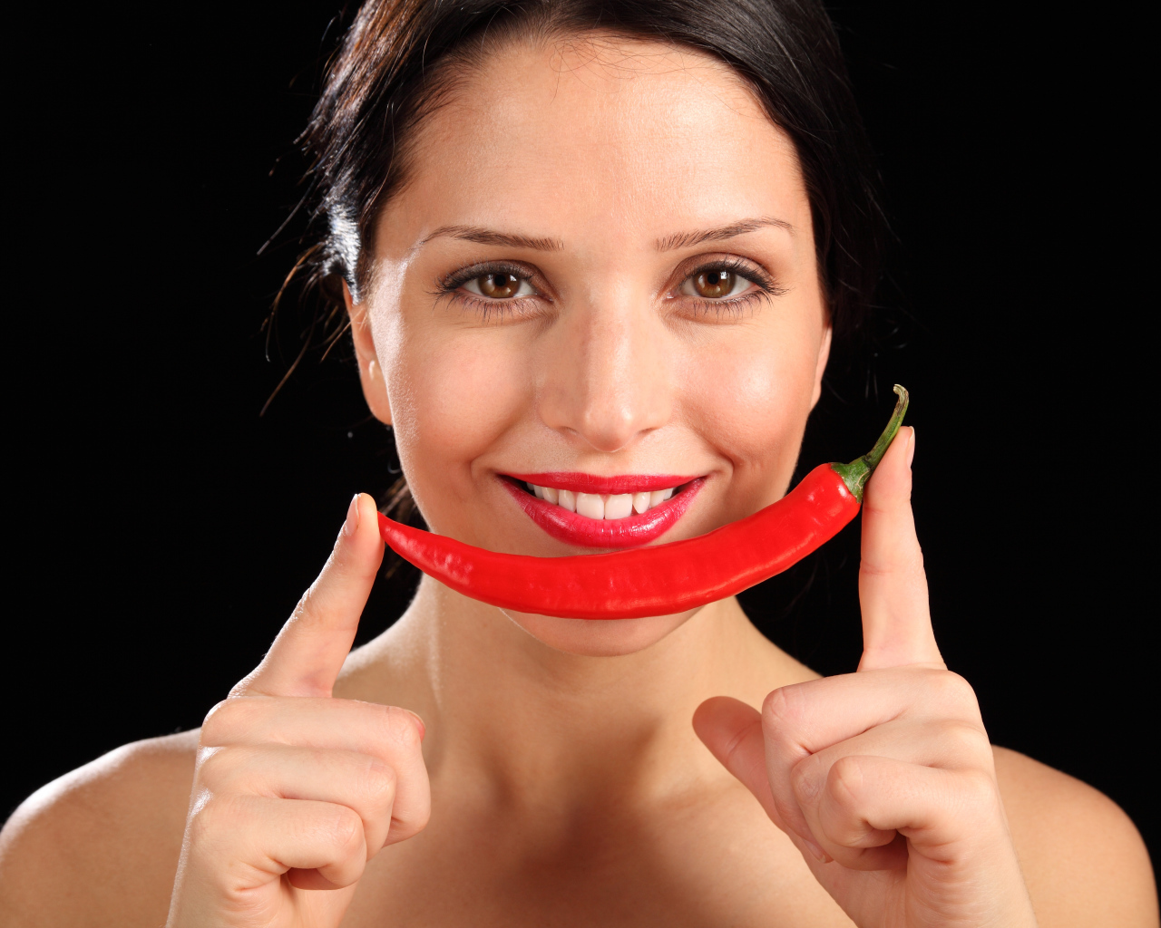 Улыбающаяся девушка с красным перцем на черном фоне