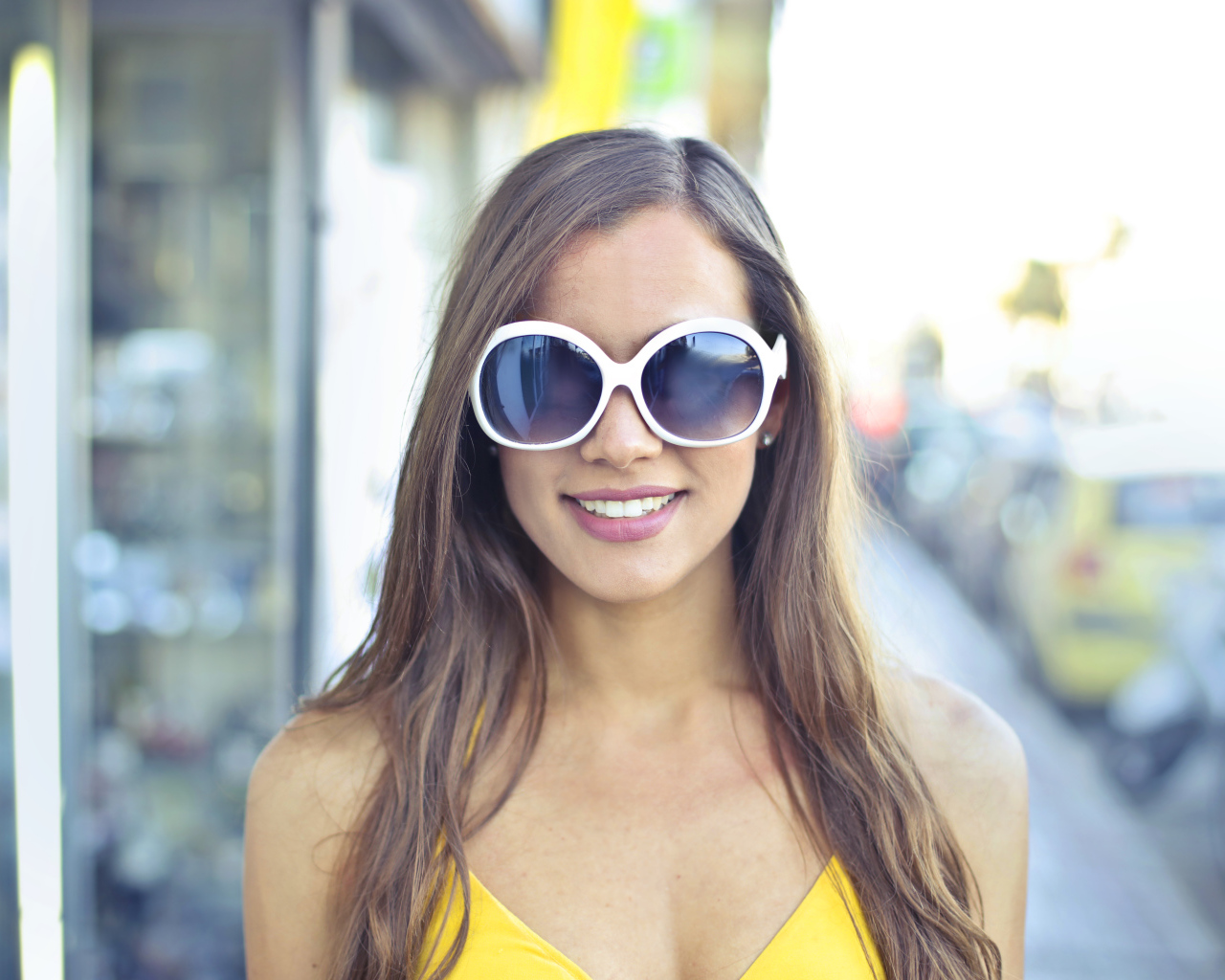 Улыбающаяся молодая девушка в солнечных очках 