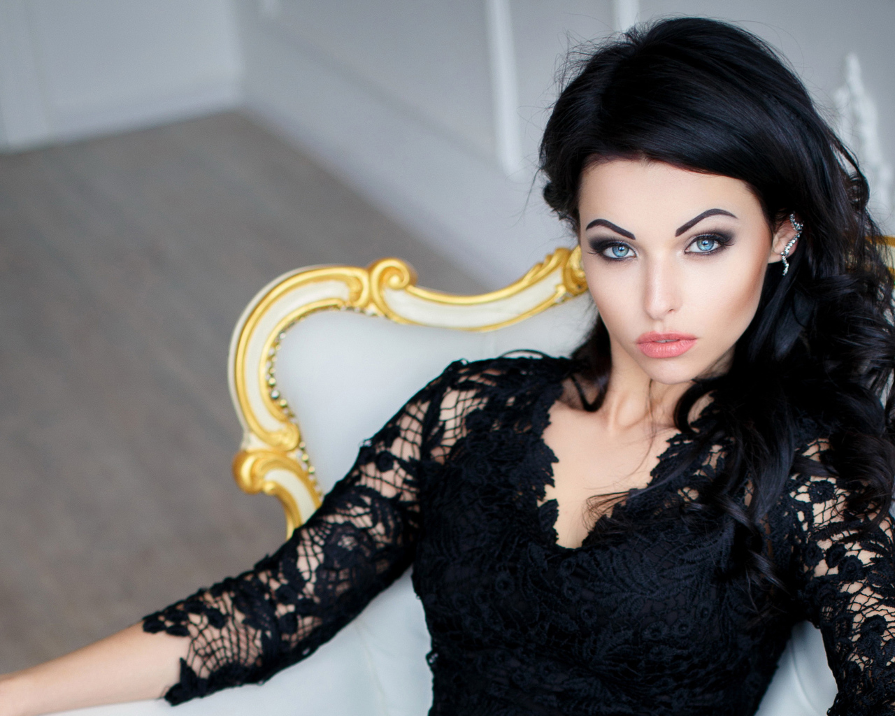 Эффектная брюнетка в черном платье сидит в кресле