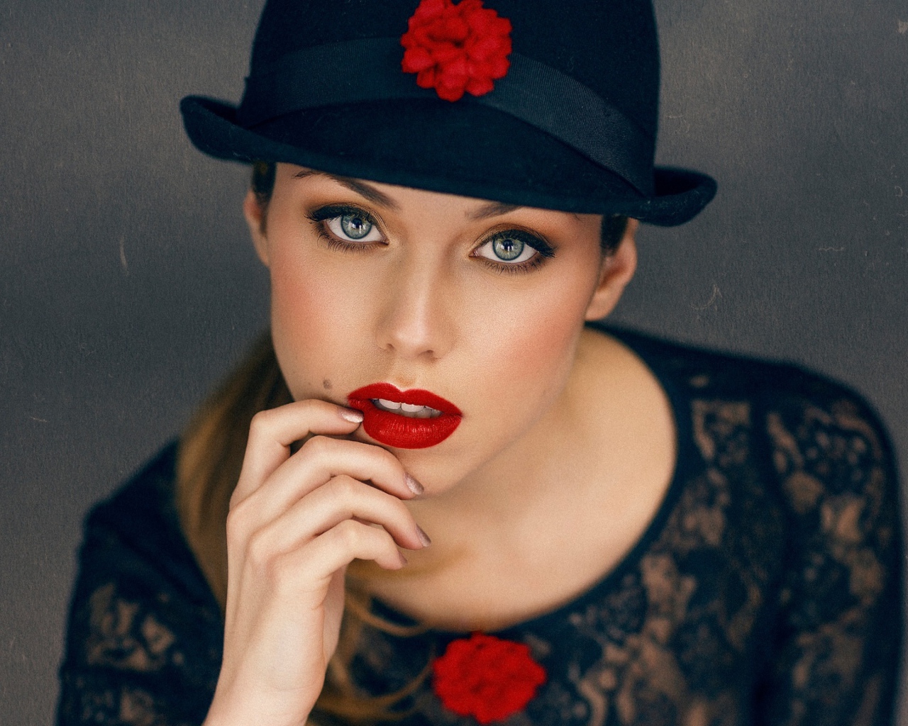 Стильная девушка с ярким макияжем в черной шляпе 