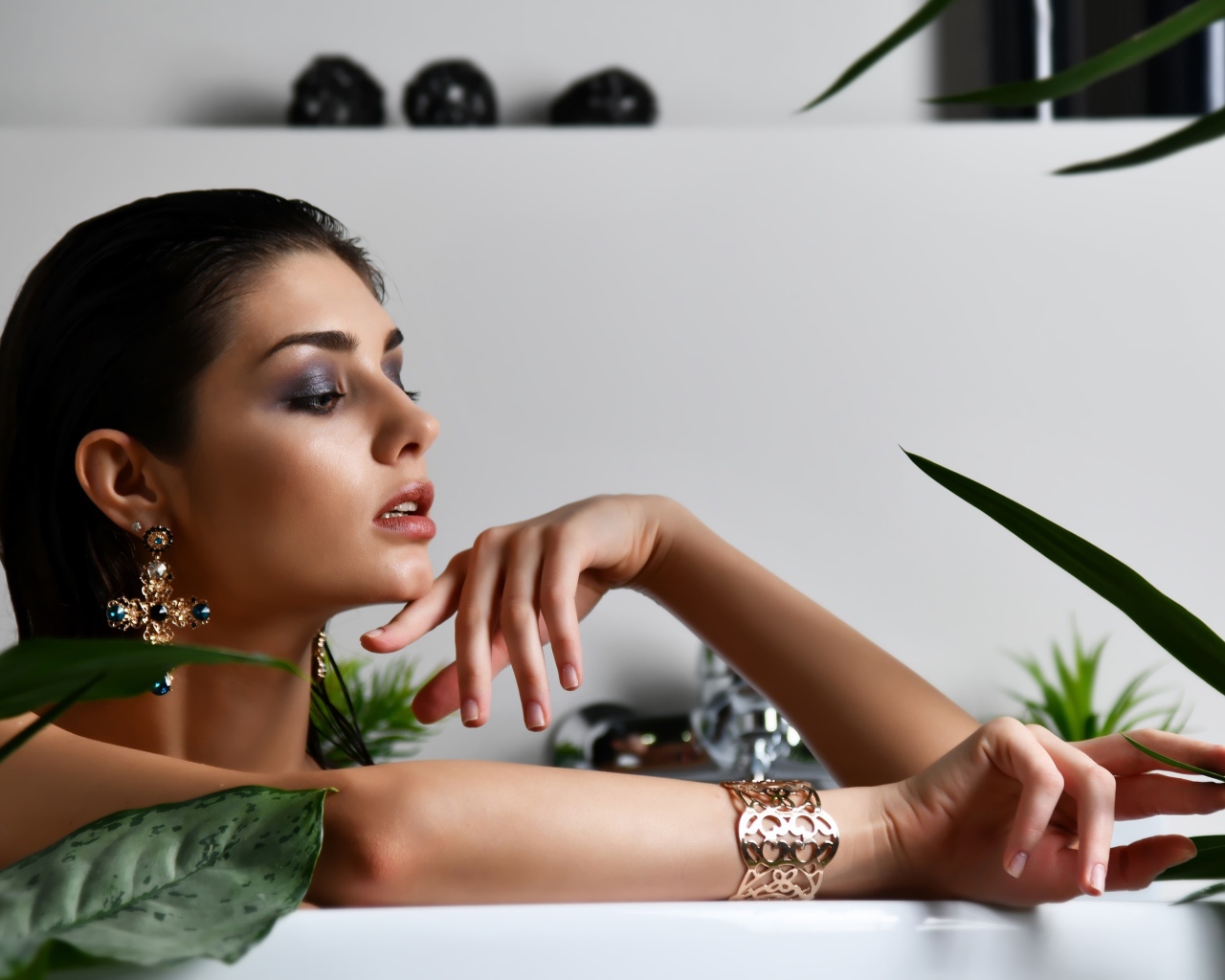 Девушка в дорогих украшения лежит в ванной