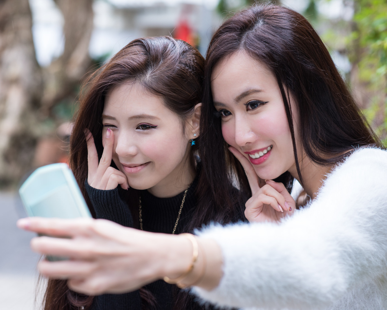 Две девушки азиатки делают селфи
