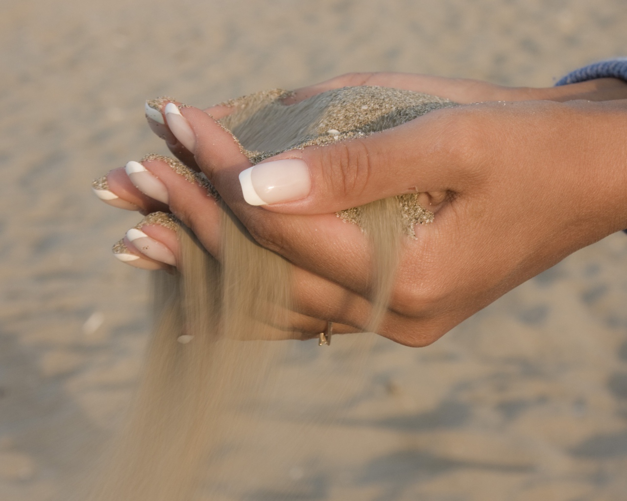 Желтый песок в руках у девушки с красивым маникюром