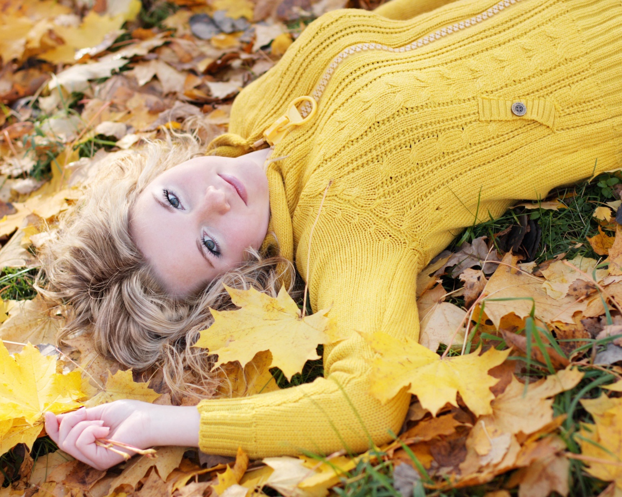 Молодая блондинка лежит на сухой листве осенью
