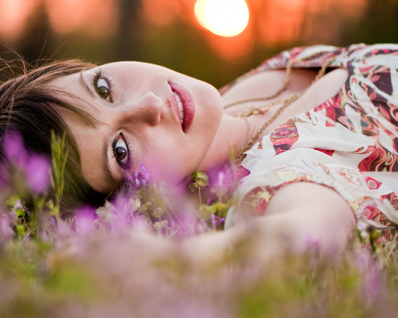 Молодая кареглазая девушка лежит на траве