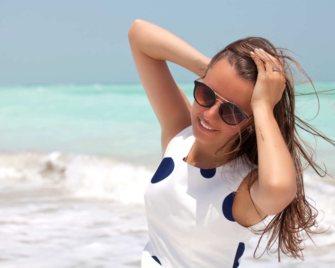 Молодая шатенка в солнечных очках у моря