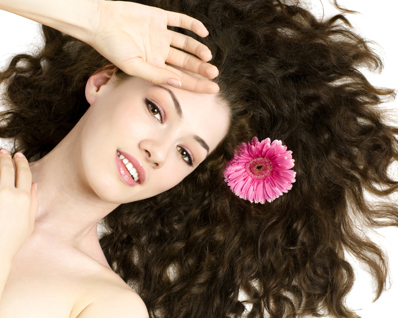 Молодая шатенка с розовым цветком герберы в волосах