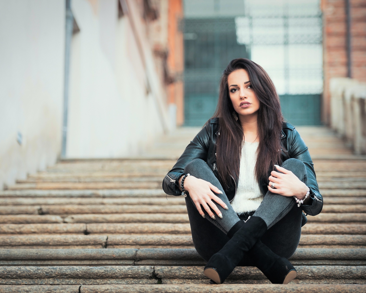 Молодая брюнетка сидит на ступеньках