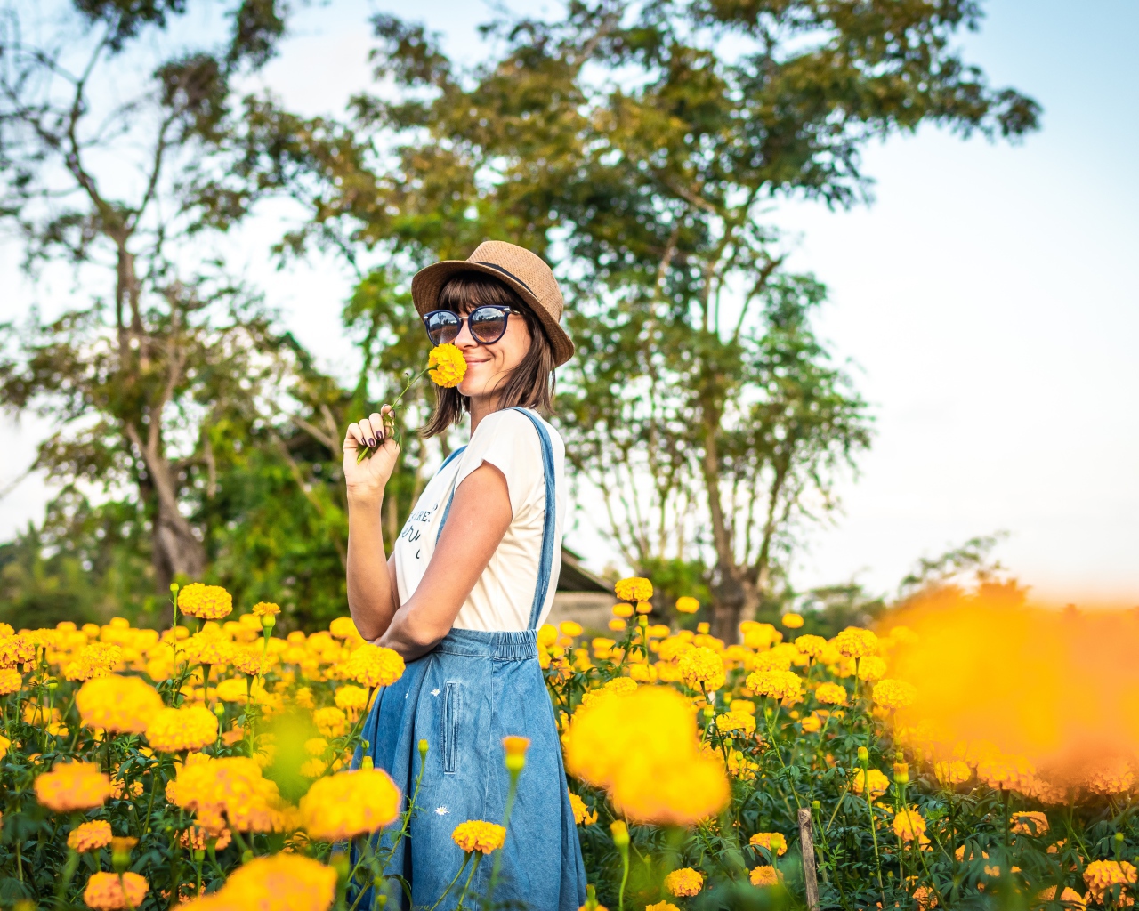 Молодая девушка в солнечных очках в желтых цветах 