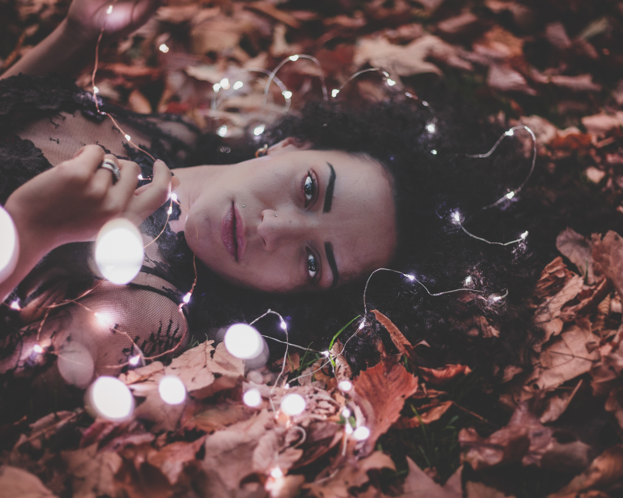 Молодая девушка лежит с гирляндой на желтых листьях