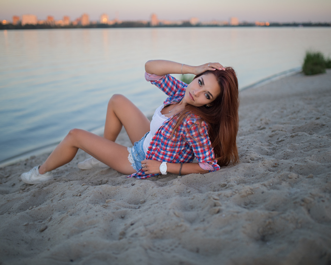 Молодая девушка лежит на песке у реки