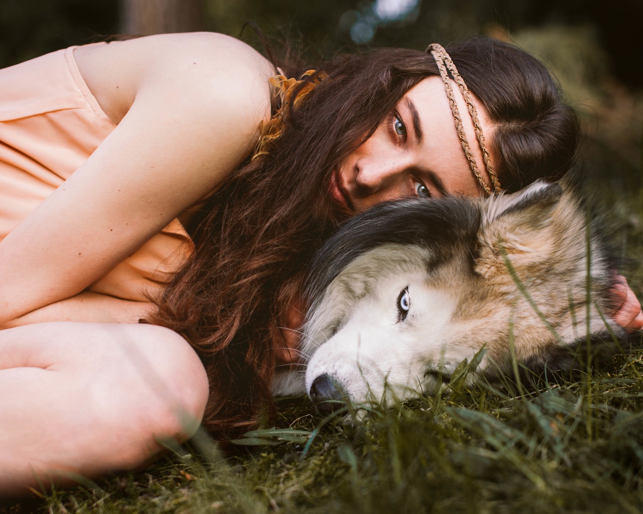 Молодая девушка с собакой породы хаски лежит на траве
